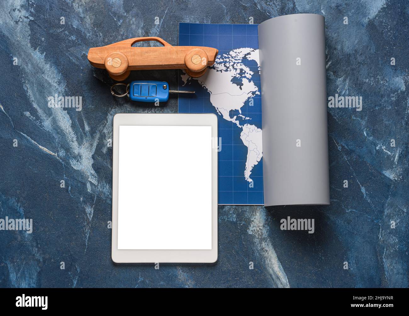Tablet computer with toy car, key and map on grunge background Stock Photo