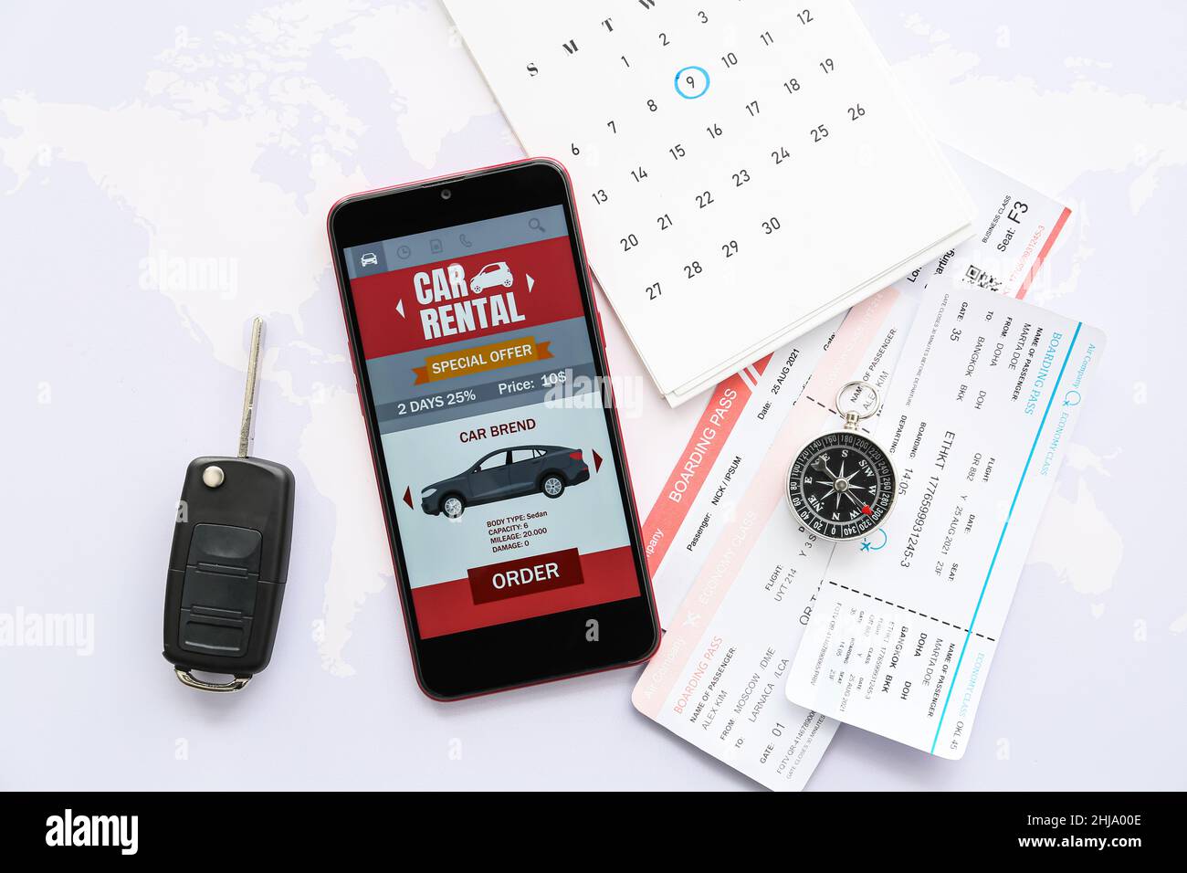 Mobile phone with open car rent app, key, compass and tickets on world ...