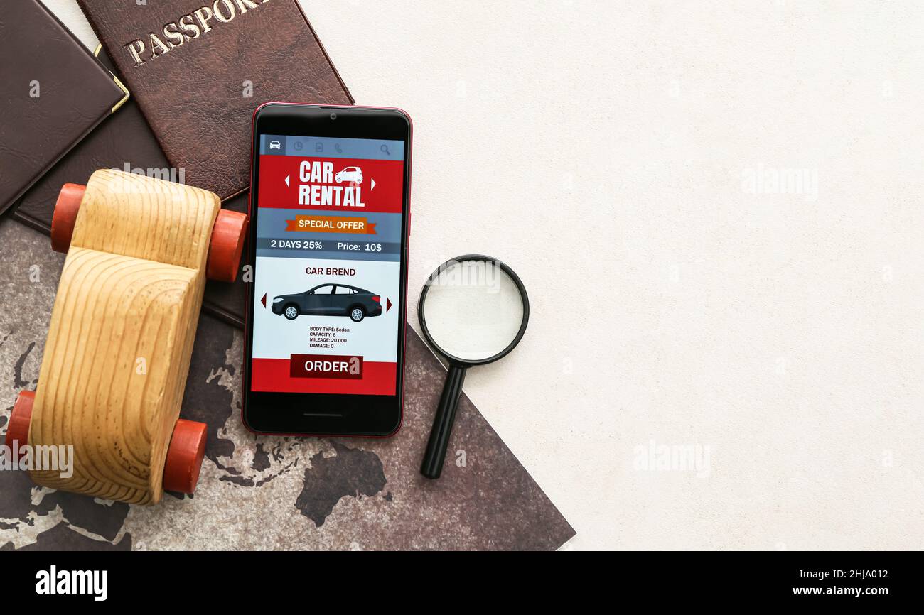 Mobile phone with open car rent app, wooden toy, magnifier, passports