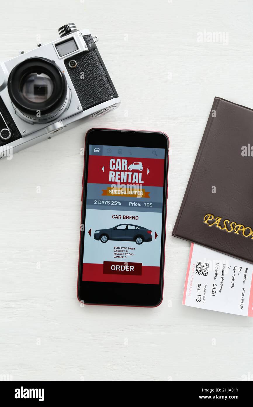 Mobile phone with open car rent app, passport and photo camera on white ...