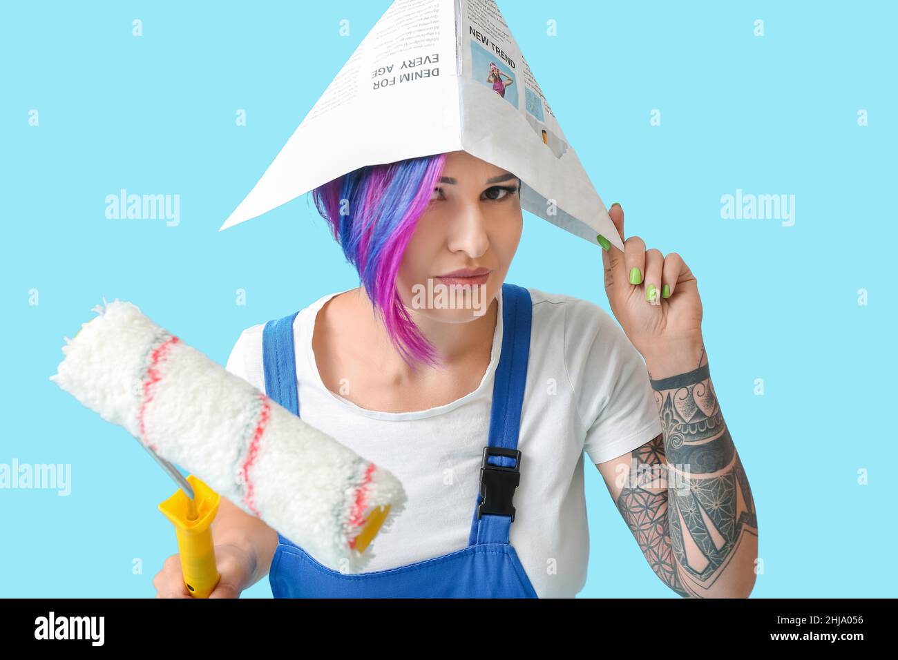 Female painter with paper hat and paint roller on blue background Stock ...