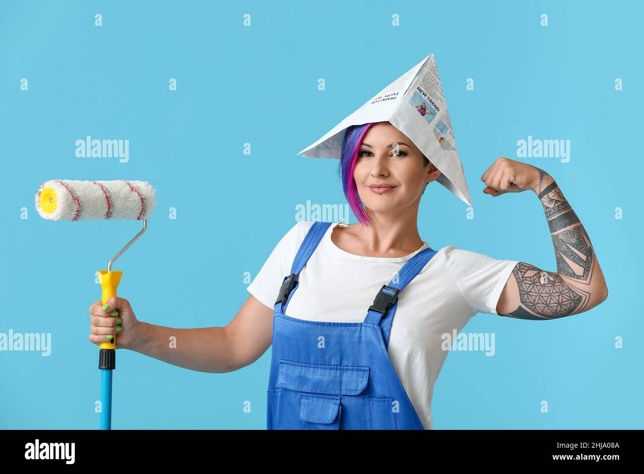 Female painter with paper hat and paint roller on blue background Stock ...