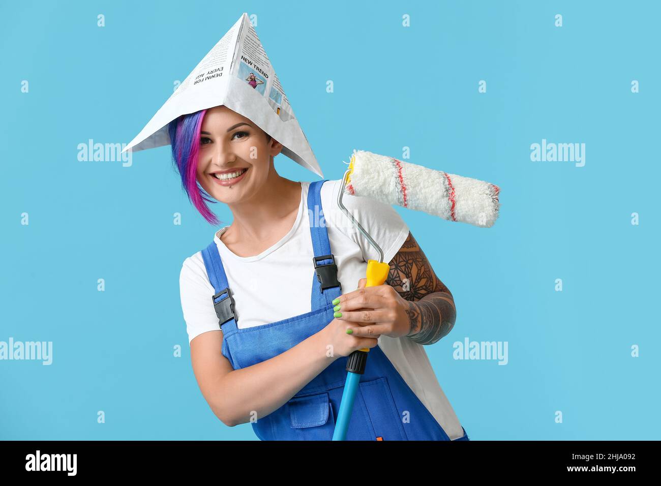 Female painter with paper hat and paint roller on blue background Stock ...