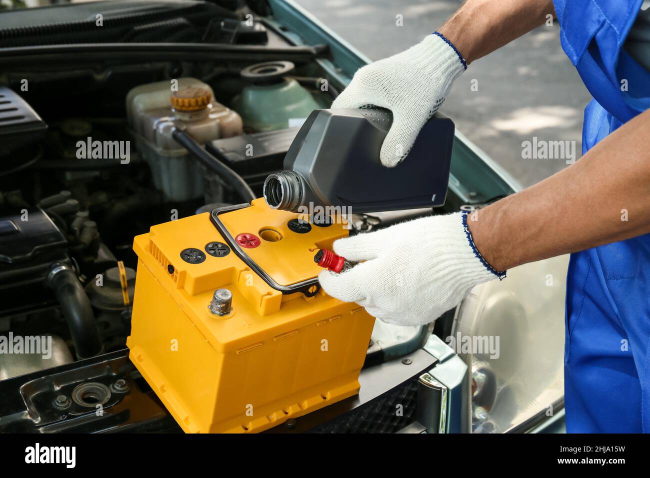 Male mechanic pouring oil into car battery Stock Photo Alamy