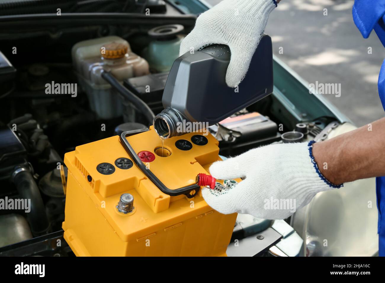 Male mechanic pouring oil into car battery Stock Photo Alamy