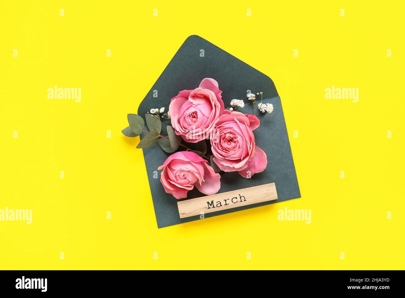Composition with envelope, beautiful flowers and word MARCH on yellow ...
