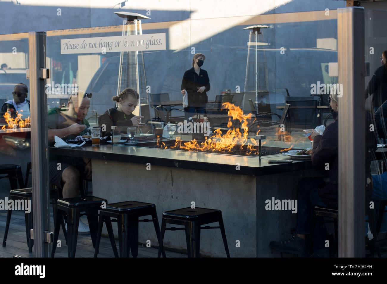 Social distanced people eating in an outdoor setting at Finns Fireside Patio, a local restaurant in Seaside, Oregon, on Saturday, January 22, 2022... Stock Photo