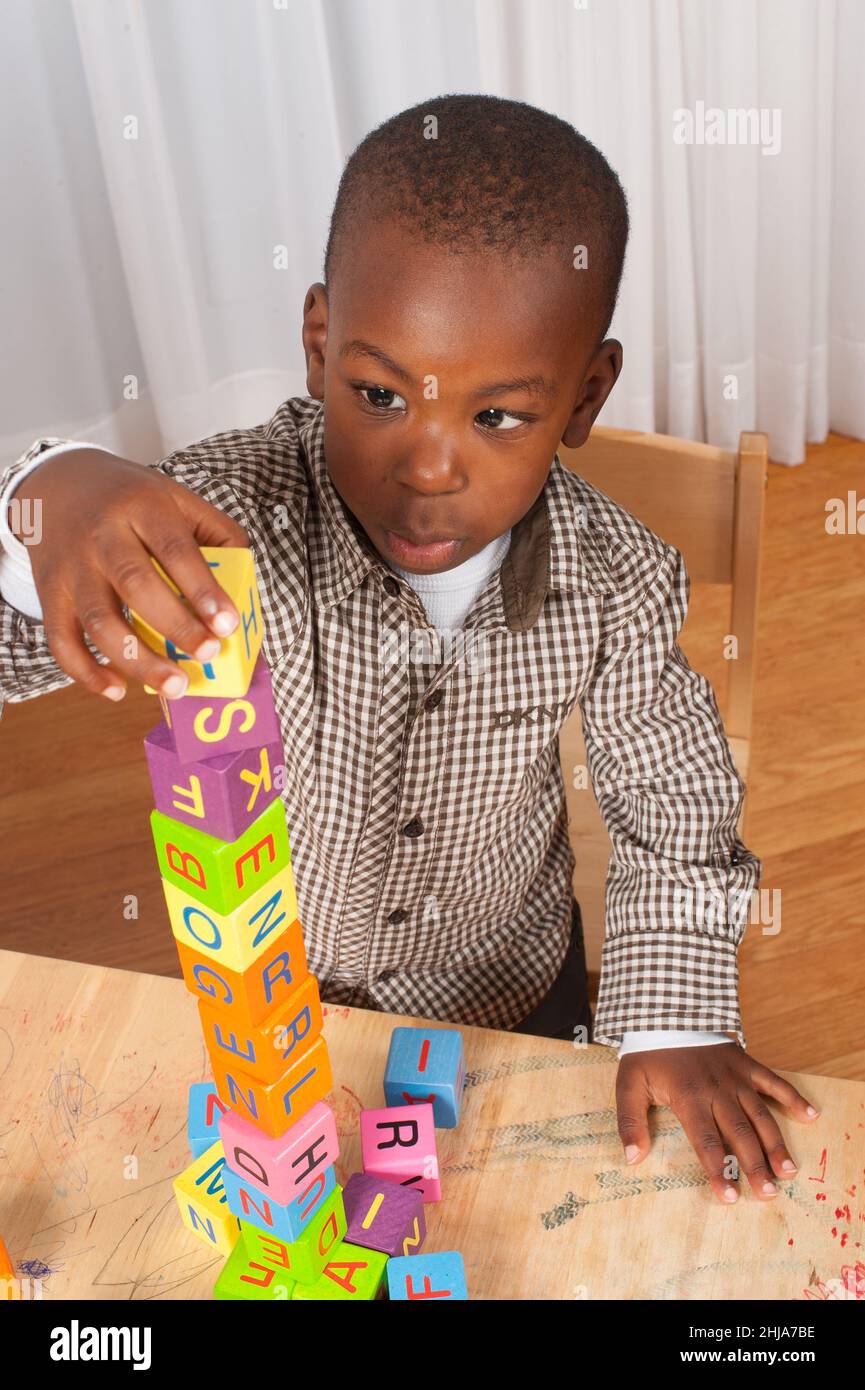 2 year old toddler boy building block tower with alphabet blocks Stock Photo