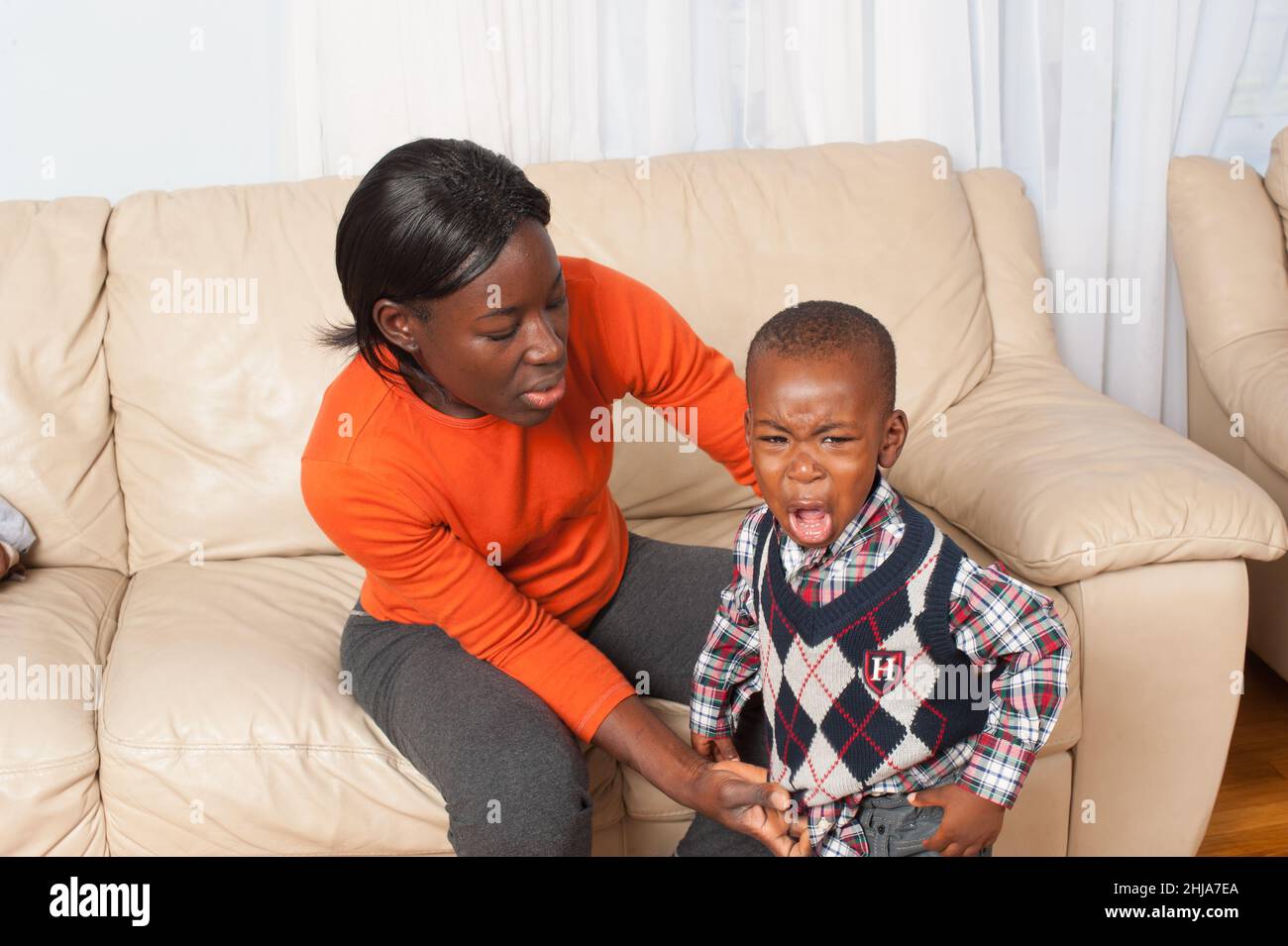 toddler boy crying about clothing change, with his mother Stock Photo