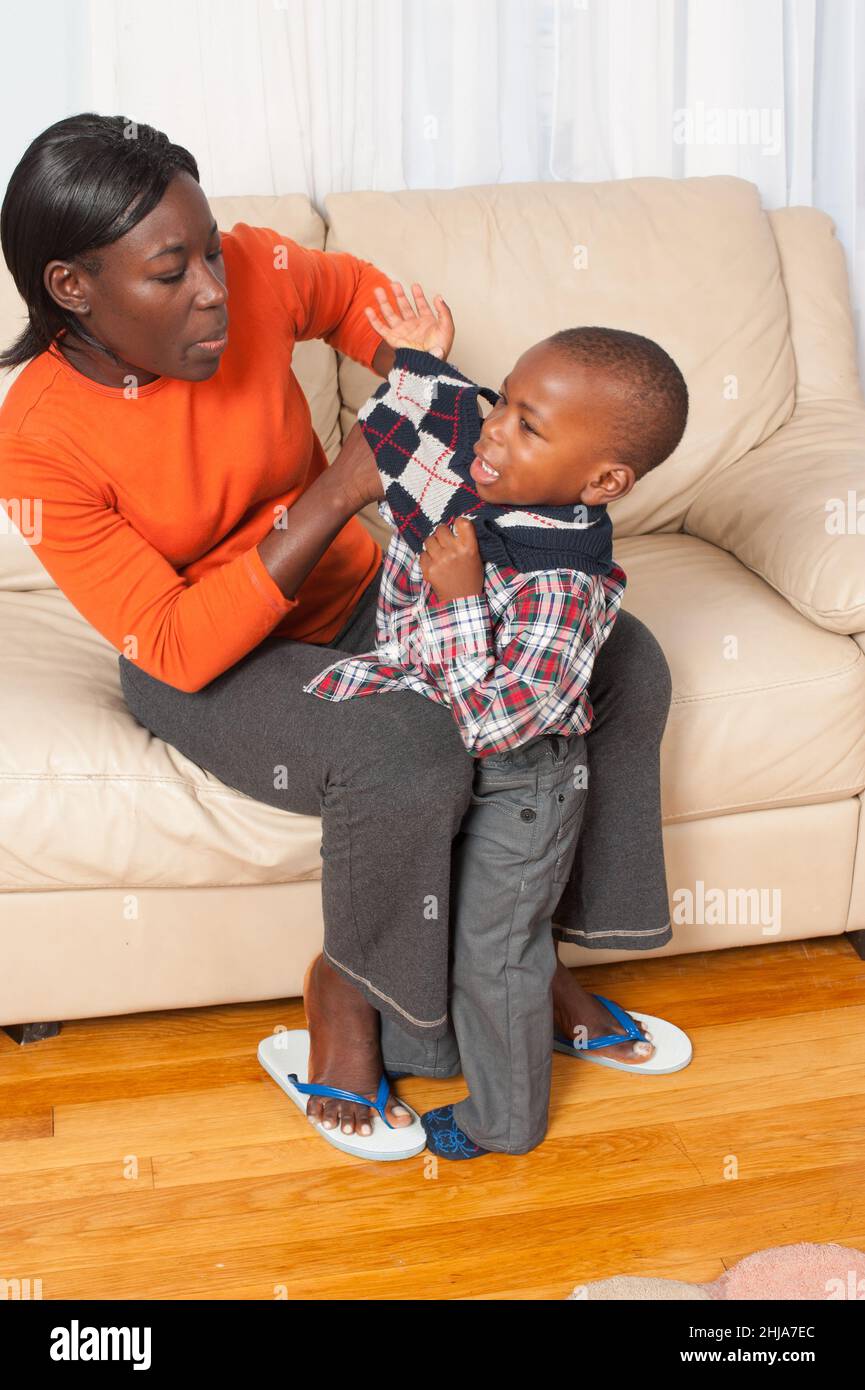 two year old boy with mother, unhappy about clothing change, crying, mother listening sympathetically Stock Photo