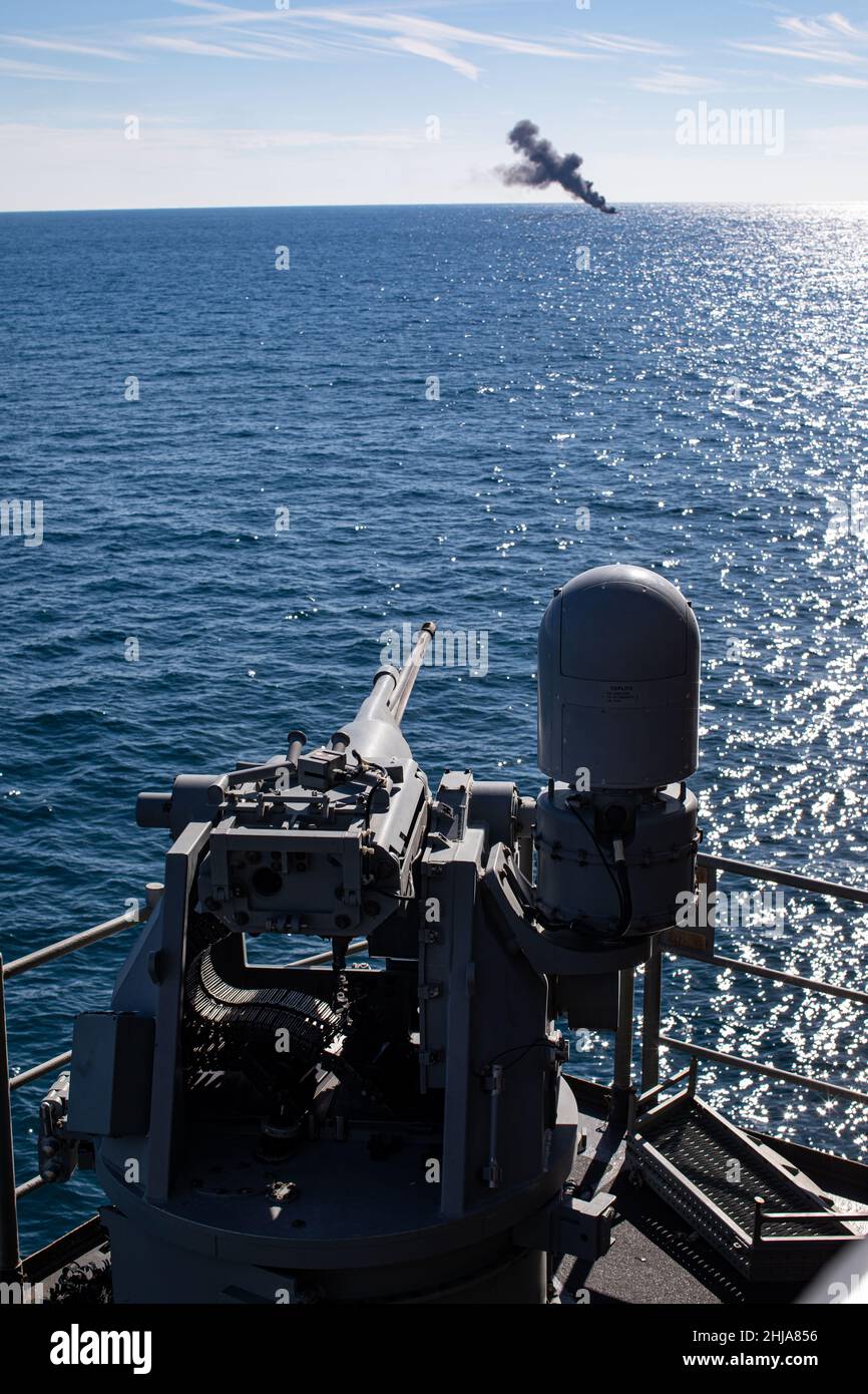 A U.S. Navy MK-38 25mm Bushmaster fires at a floating target during a live-fire training evolution during Composite Training Unit Exercise (COMPTUEX) aboard the USS Kearsarge (LHD 3), Jan. 24, 2022. The 22nd Marine Expeditionary Unit and Amphibious Squadron (PHIBRON) Six are underway for COMPTUEX in preparation for an upcomingdeployment. COMPTUEX is the last at-sea period in the MEU’s Predeployment Training Program; it aims to test the capabilities of the ARG/MEU and achieve deployment certification. (U.S. Marine Corps photo by Sgt. Armando Elizalde) Stock Photo