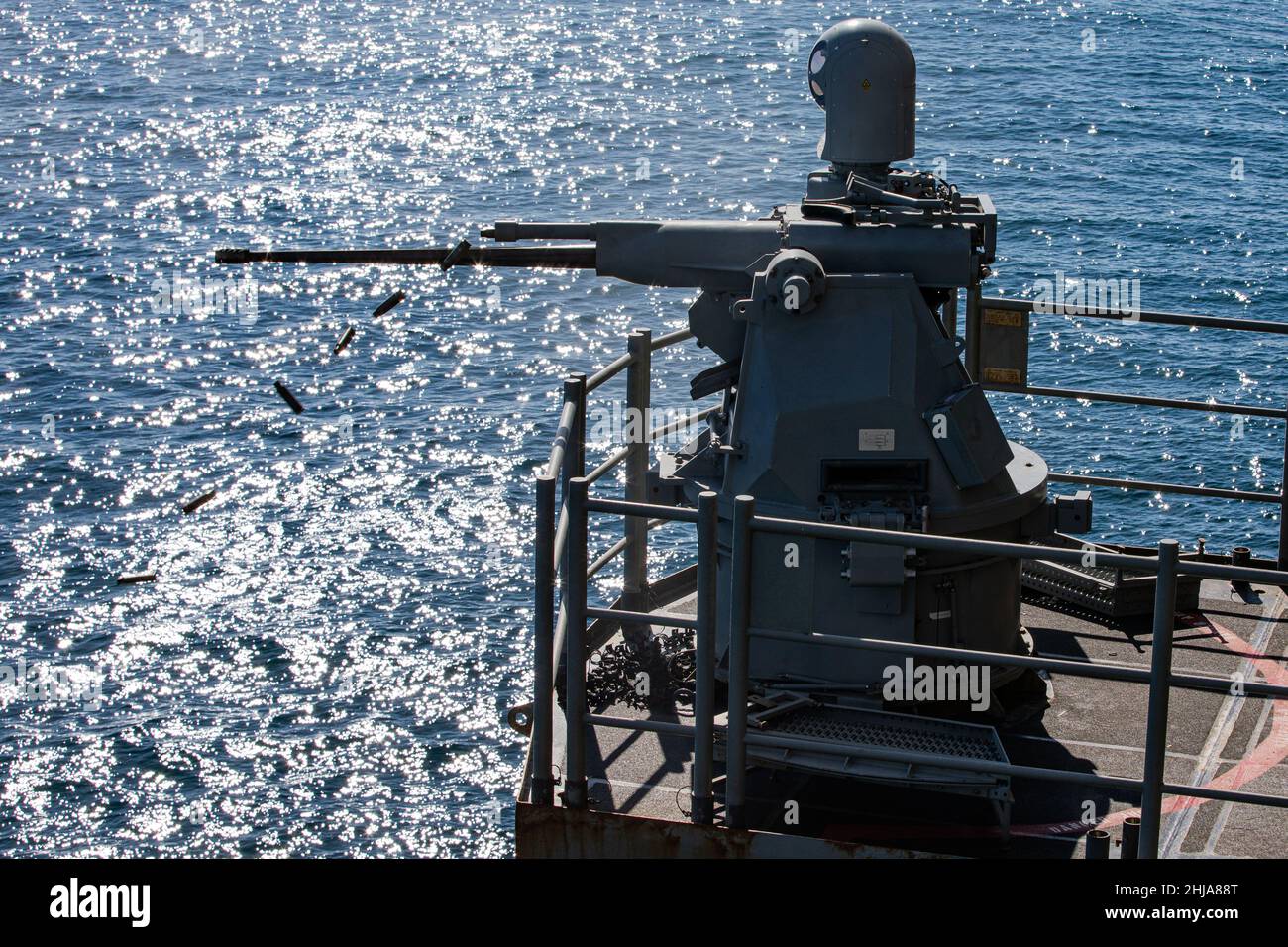 A U.S. Navy MK-38 25mm Bushmaster fires at a floating target during a live-fire training evolution during Composite Training Unit Exercise (COMPTUEX) aboard the USS Kearsarge (LHD 3), Jan. 24, 2022. The 22nd Marine Expeditionary Unit and Amphibious Squadron (PHIBRON) Six are underway for COMPTUEX in preparation for an upcomingdeployment. COMPTUEX is the last at-sea period in the MEU’s Predeployment Training Program; it aims to test the capabilities of the ARG/MEU and achieve deployment certification. (U.S. Marine Corps photo by Sgt. Armando Elizalde) Stock Photo