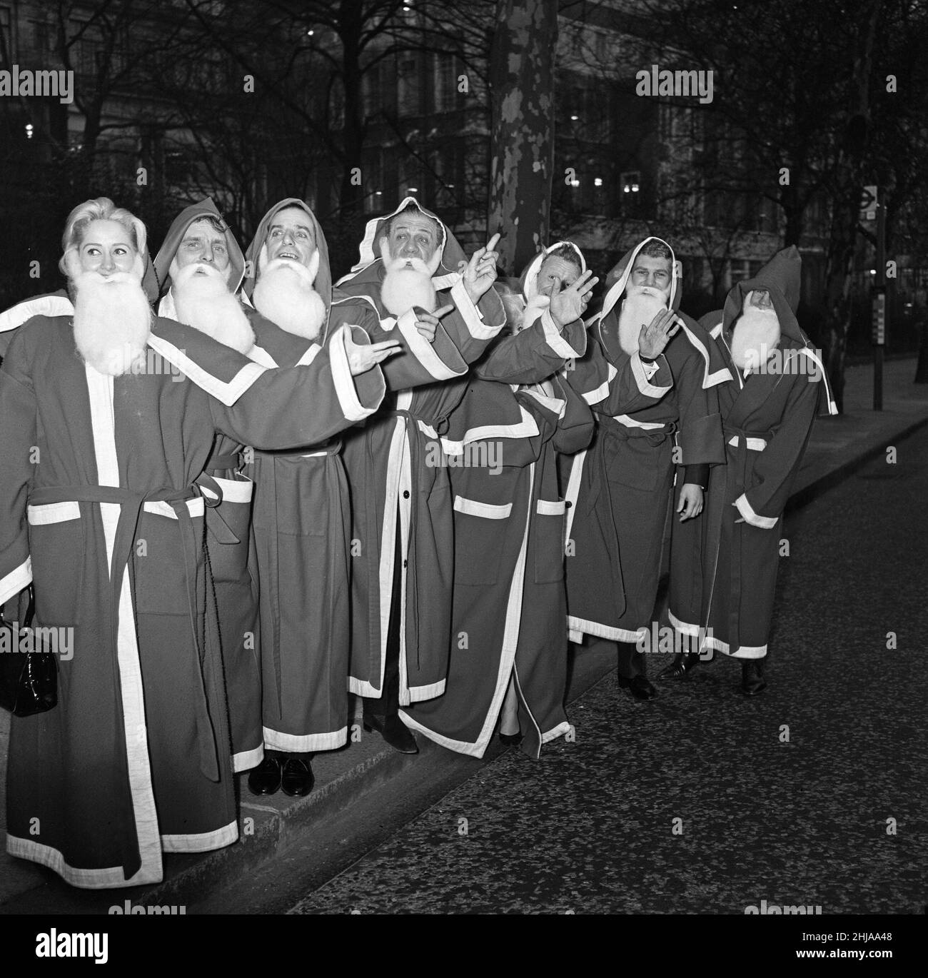 Twelve leading show business personalities are to act as 'Father Christmasses' at the Variety Club of Great Britain's Christmas Luncheon at the Savoy Hotel, when the club's annual drive to collect a minimum of 15,000 toys for children in hospitals, orphanages, homes and residential schools reaches its climax. The famous Father Christmas's waiting at a bus-stop on the Embankment are L-R Liz Fraser, Dickie Henderson, Ben Warriss, Sid James, Barbara Windsor, Jon Pertwee, Billy Walker, Terry Downes. 10th December 1963. Stock Photo