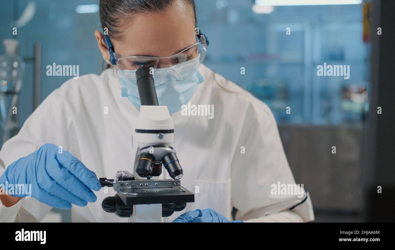 Specialist working with microscope in science laboratory, using