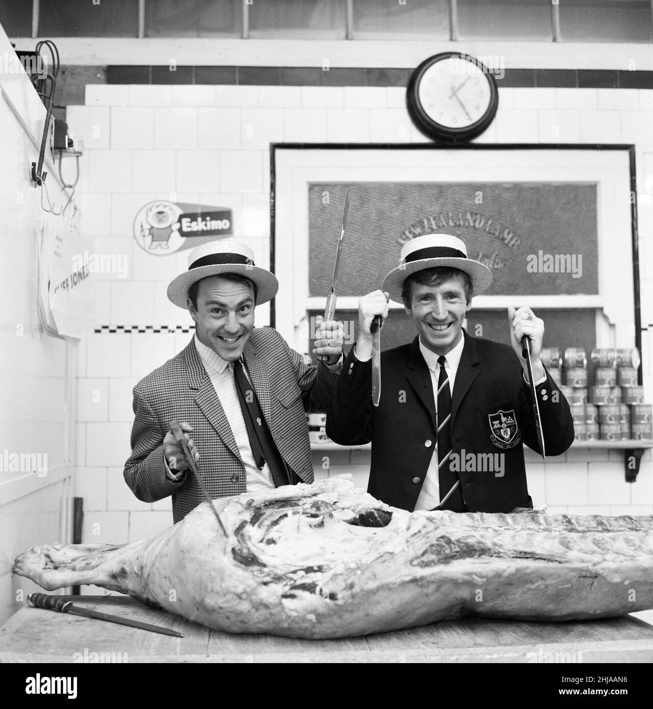 Tottenham Hotspur and Wales footballer Cliff Jones, invites teammates to Arnos Grove in London where he opened a second butchers shop.Carving a side of beef in their butcher hats are left to right: Jimmy Greaves and Cliff Jones. 17th September 1964. Stock Photo