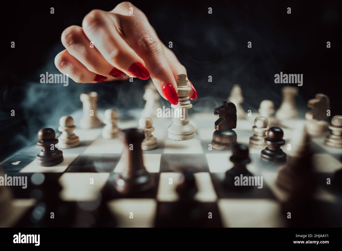 Concept: the woman who dominates the man. A woman's hand gives checkmate to  the king with the queen on a wooden chessboard, with no other pieces in  play Stock Photo
