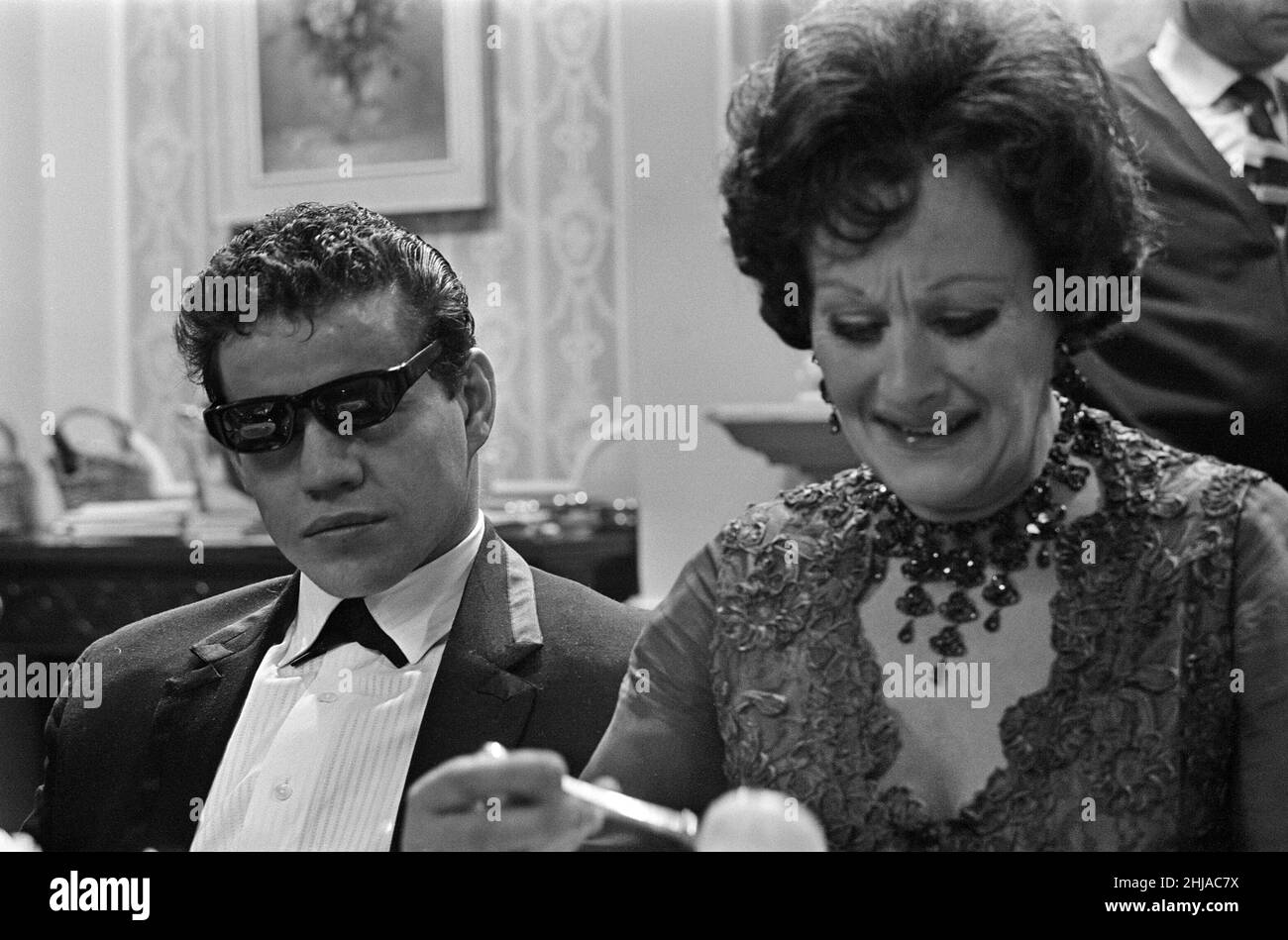 Filming on the set of the film 'Darling'. Unidentified man on the left, and Fanny Cradock on the right.   Darling is a 1965 British drama film written by Frederic Raphael, directed by John Schlesinger, and starring Julie Christie with Dirk Bogarde and Laurence Harvey.  Darling was nominated for five Academy Awards, including Best Picture and Best Director. Christie won the Academy Award for Best Actress for her performance as Diana Scott. The film also won the Academy Awards for Best Original Screenplay and Best Costume Design.  Picture taken 16th December 1964 Stock Photo
