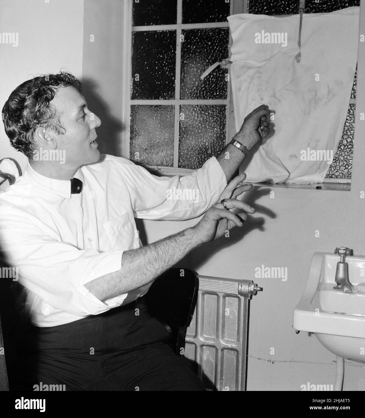 American singer Carl Perkins points to a smashed window in his dressing room at the Odeon Cinema, Hammersmith after a stone was thrown grazing his hand. 31st May 1964. Stock Photo