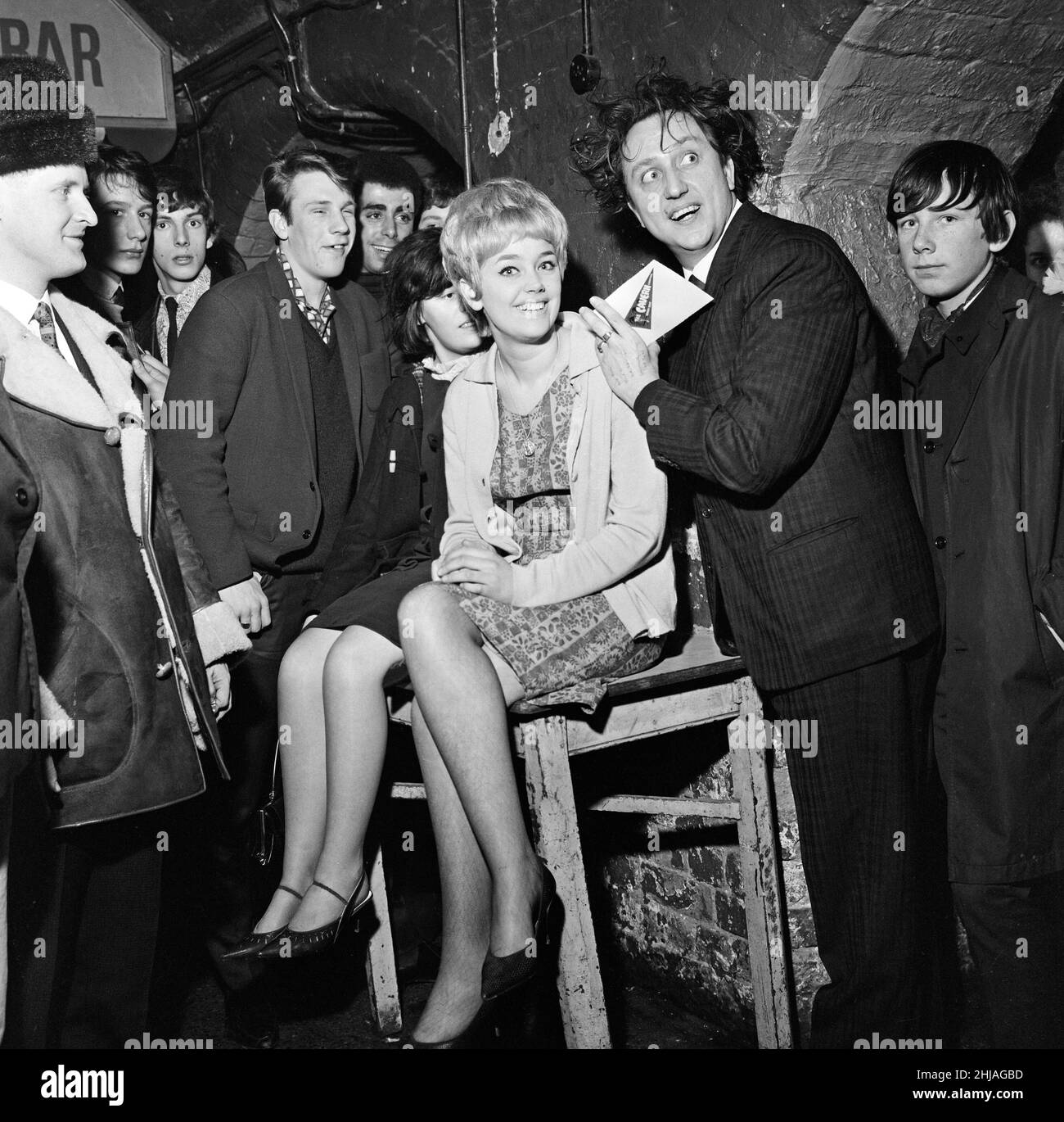 Comedian Ken Dodd was made the first honorary life member of Liverpool Cavern Club. Ken signs his application form on the back of Margaret Johnson, 19, of Anfield, Liverpool.  24th January 1964. Stock Photo
