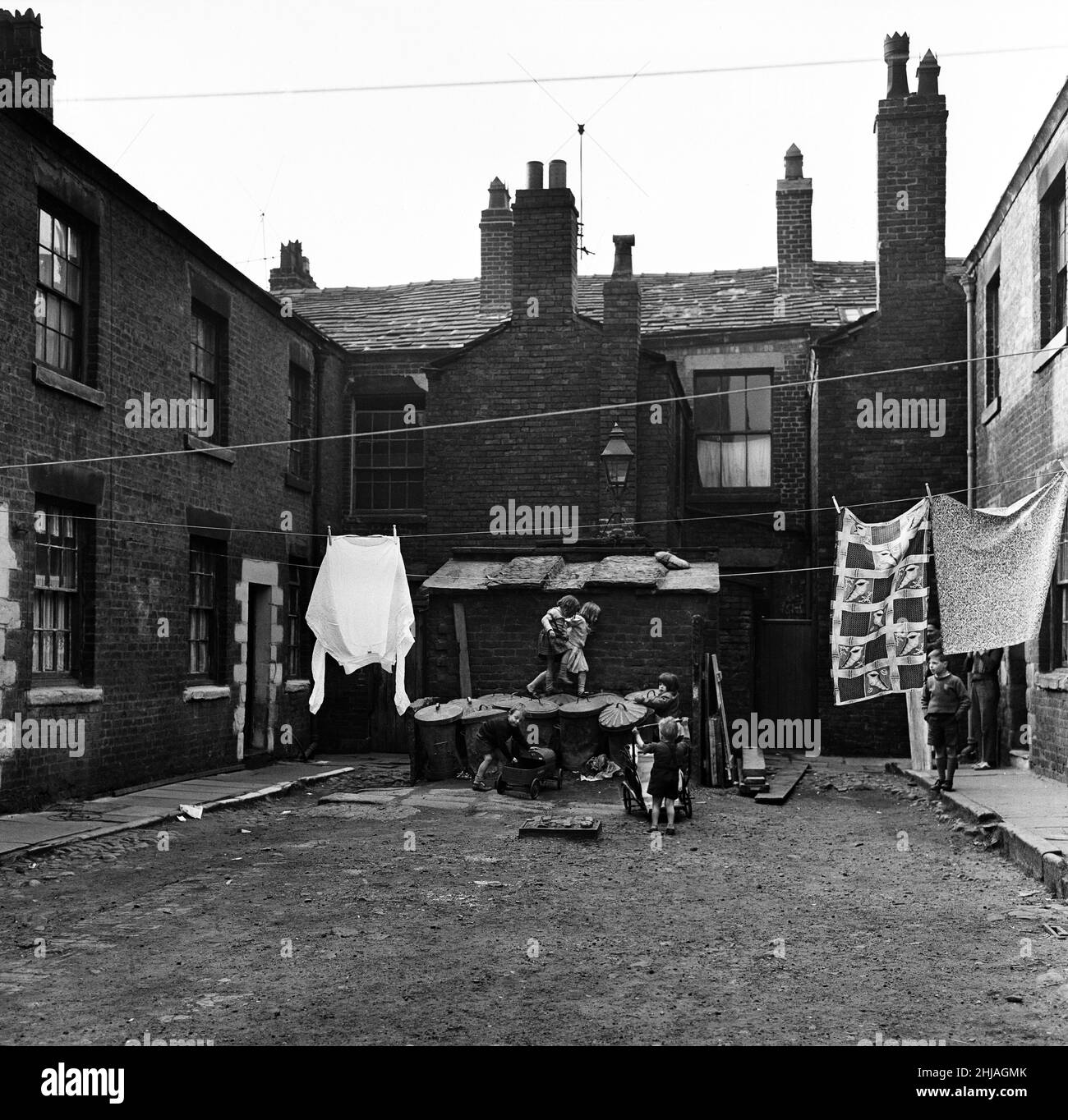 Children playing outside slum housing Number Two Court, Dickenson Street, Oldham. 1st June 1962. Stock Photo