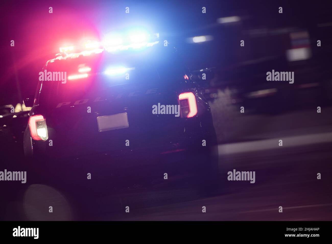 American Police SUV Cruiser with Flashing Lights in Night Time Action. Law Enforcement Theme. Stock Photo
