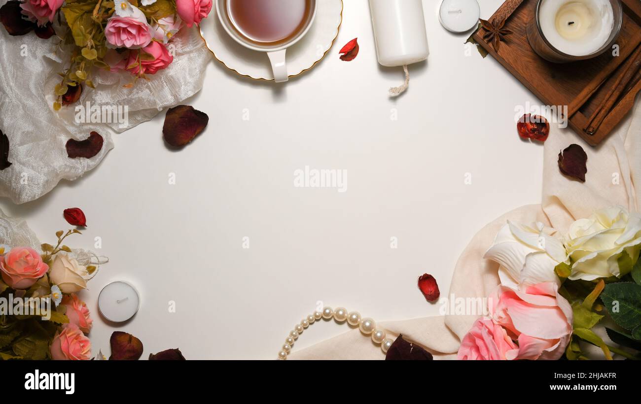 Feminine workspace with copy space, roses bouquet, candles, textiles, and decor on white background. top view, flat lay Stock Photo
