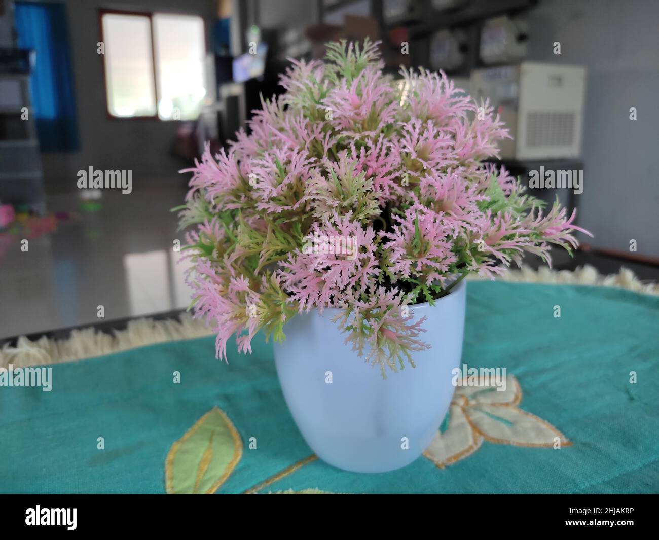 artificial pink flowers in white vase on table Stock Photo