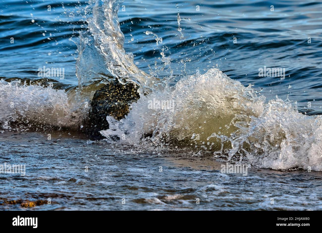 A wave splashing on a rock resting on the shore on Vancouver Island in British Columbia Canada. Stock Photo