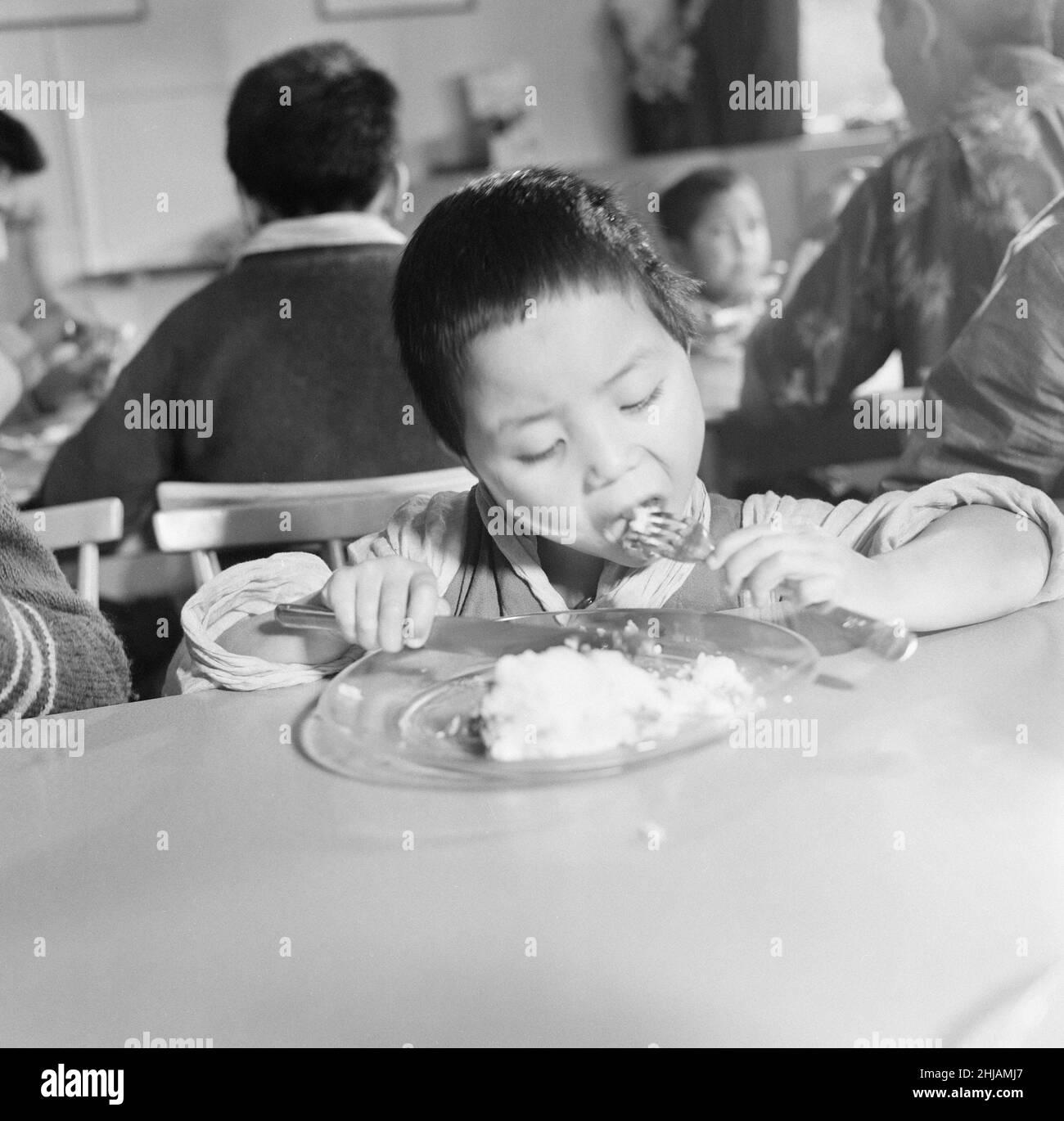 Tibetan Refugee Children at Pestalozzi Village for Children in Sedlescombe, East Sussex, 7th March 1963. Our Picture Shows ... close up of youngest child, Sonam Kiypa, eating lunch.   The thirteen boys and eight girls arrived in the UK, from a refugee camp in northern India. Many now orphaned, the children have fled chinese occupation and persecution.   The community is named after eighteenth century Swiss educationalist, Johann Heinrich Pestalozzi, who devoted his life to closing divisions in society through education of the whole person, their Head, Heart and Hands. Stock Photo