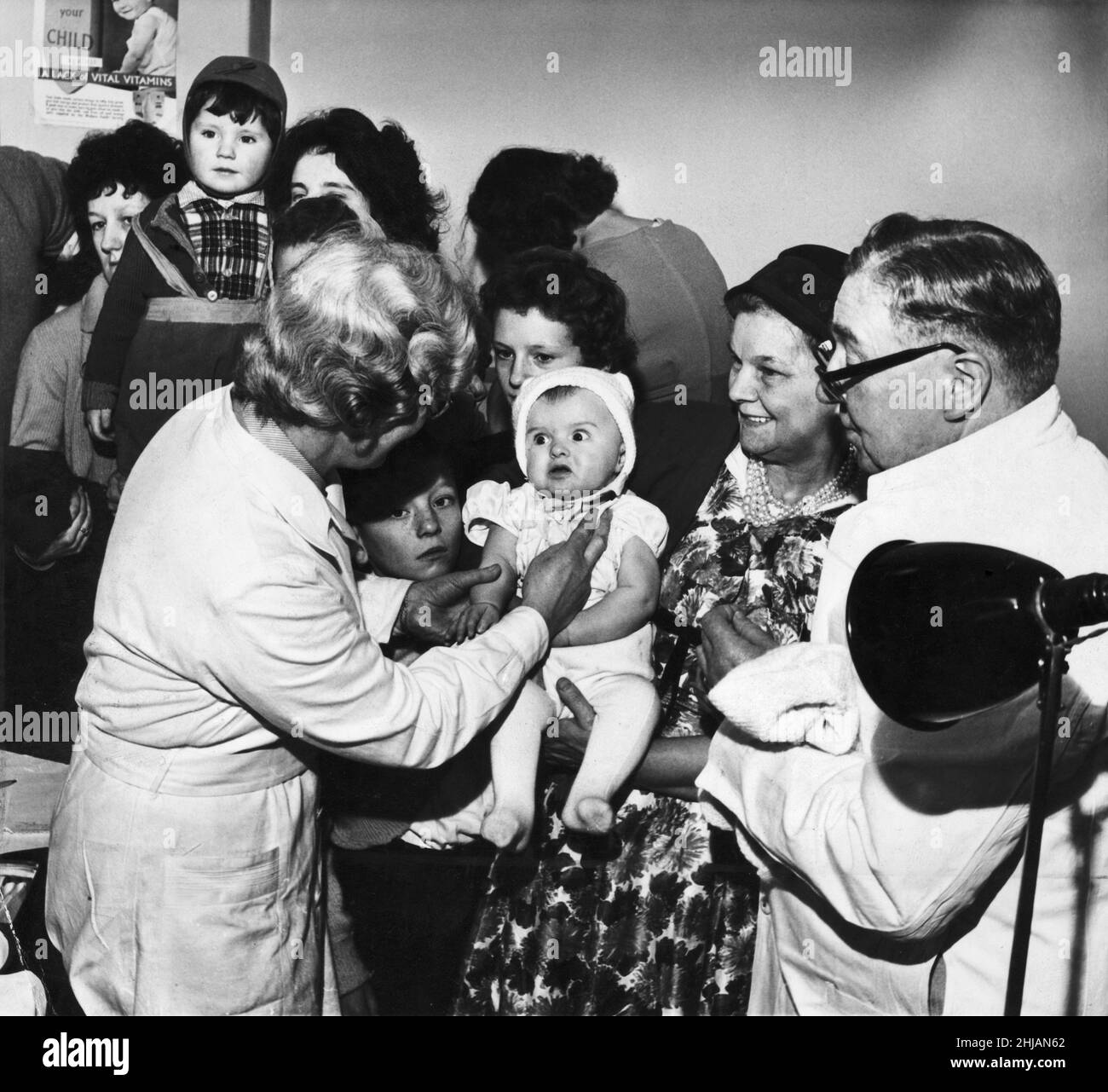 A baby being vaccinated at Halton Road divisional health centre in Runcorn, looking dismayed by quickly reassured by the nurse. More than 500 people visited the clinic to dat for their smallpox vaccination following the recent outbreak.29th January 1962. Stock Photo