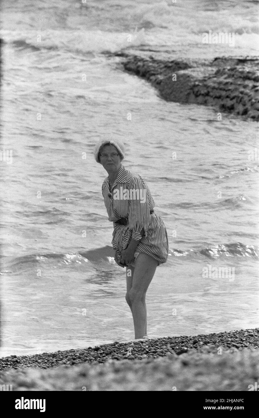 Holiday scenes at Brighton Elderly women paddling on the beach holding her skirt so it won't get wet. 7th July 1963 Stock Photo