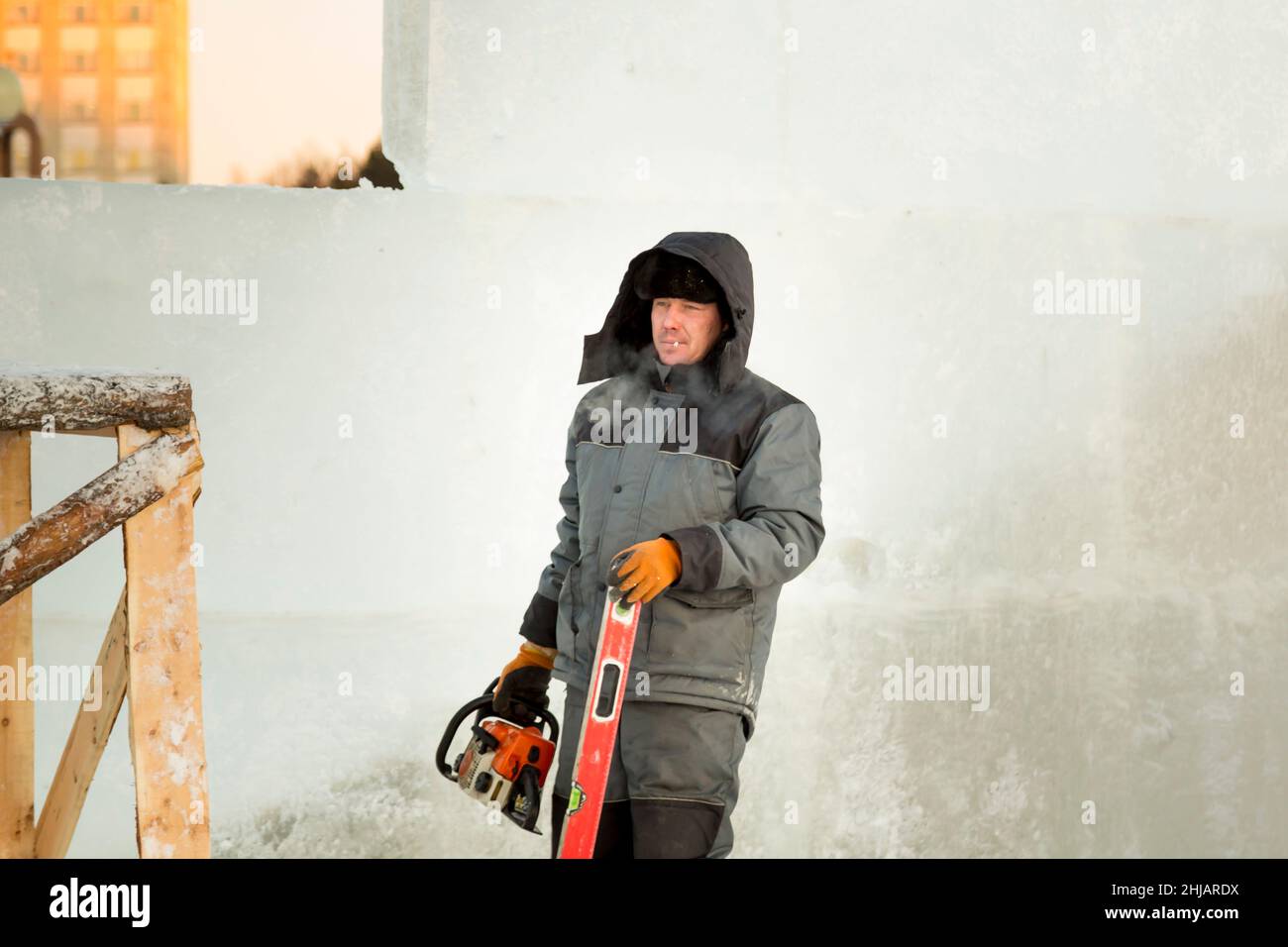 Worker with a chainsaw in hand at the assembly site Stock Photo