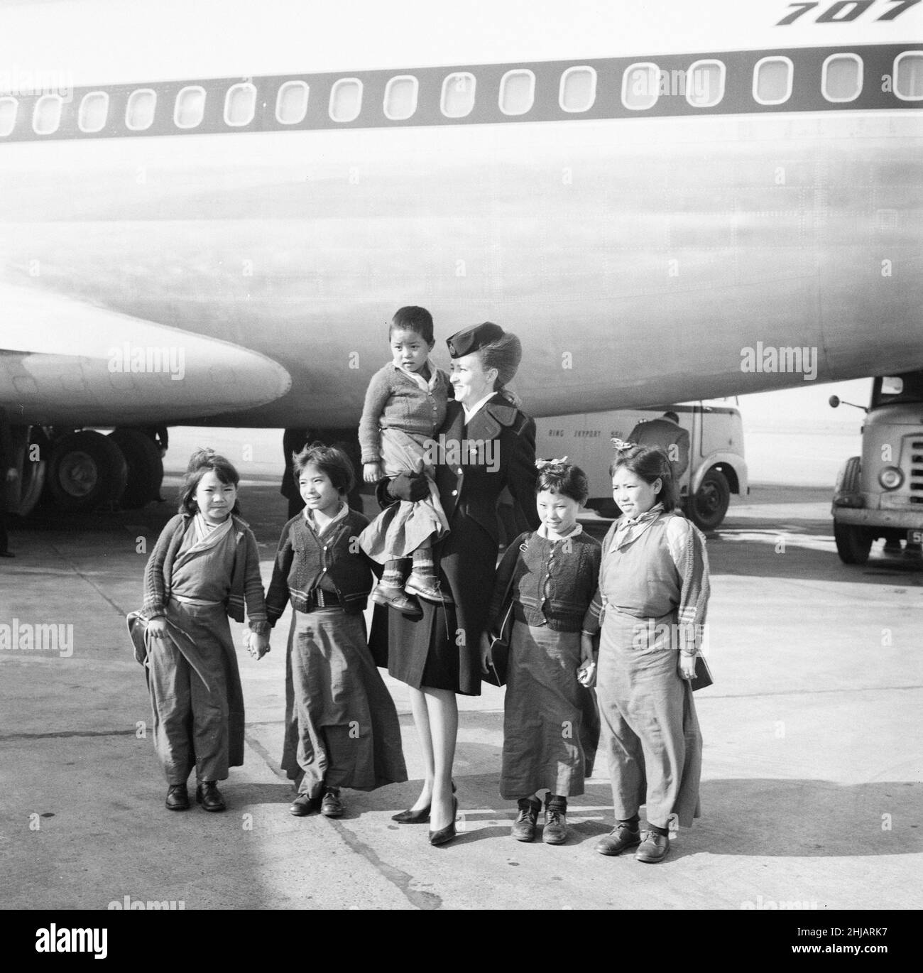 21 Tibetan Refugee Children land at London Heathrow Airport, Tuesday 26th February 1963. A BOAC Airliner brings the thirteen boys and eight girls to the UK, from a refugee camp in northern India. Many now orphaned, the children have fled chinese occupation and persecution.   Our Picture Show ... a BOAC air hostess leads six tibetan refugees away from aircraft.   The children are to be relocated to the Pestalozzi Village for Children in Sedlescombe, East Sussex, which will be their new home for the next ten years.   The community is named after eighteenth century Swiss educationalist, Johann He Stock Photo
