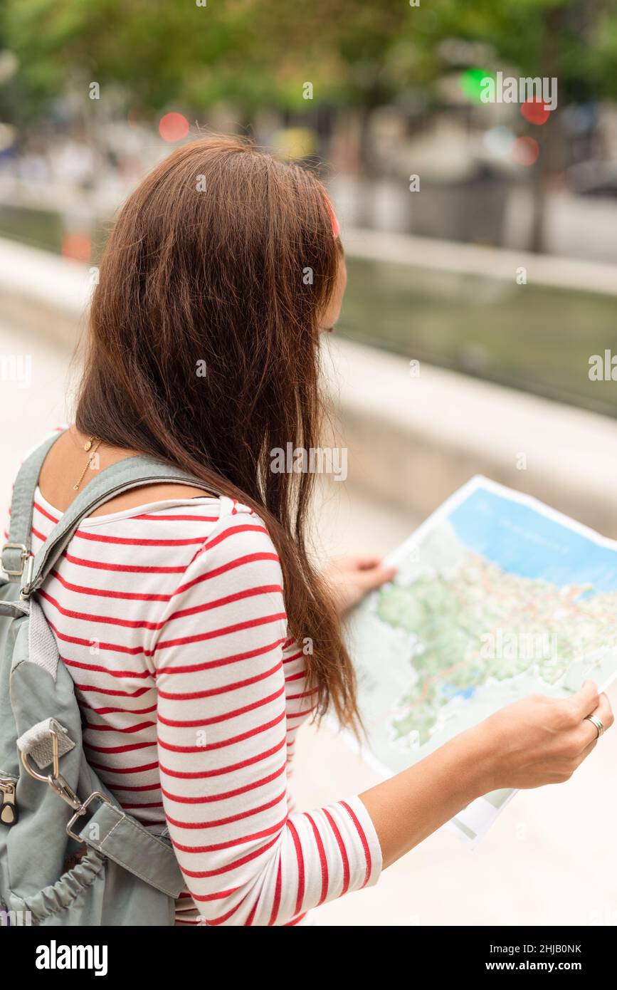Anonymous woman with backpack and map in city Stock Photo