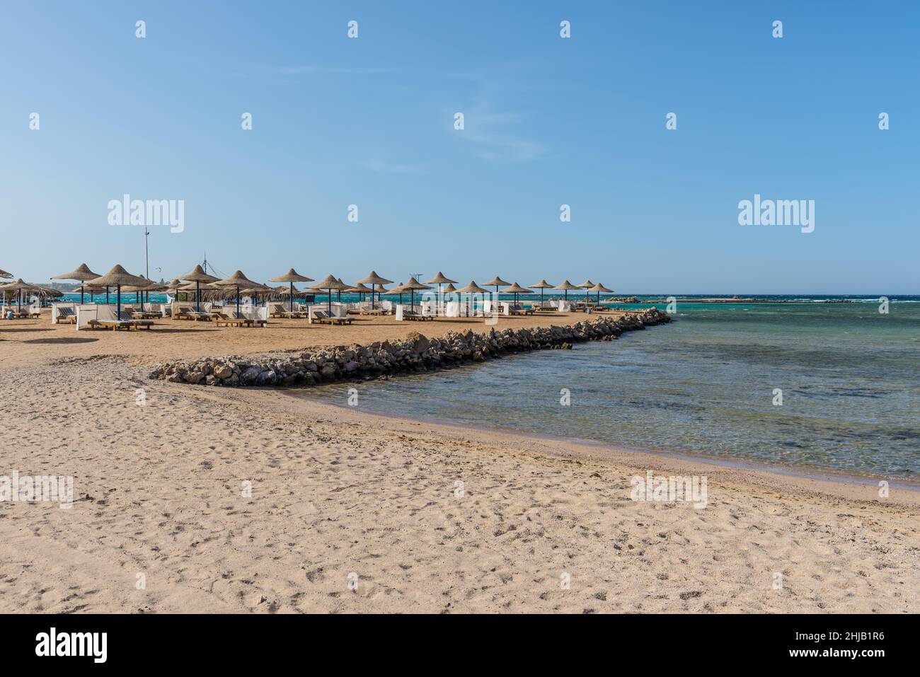 Hurghada, Egypt - June 03, 2021: Umbrellas and sun loungers on an empty beach of the Royal Pharaohs Makadi Bay, which one of Egypt beautiful Red Sea R Stock Photo