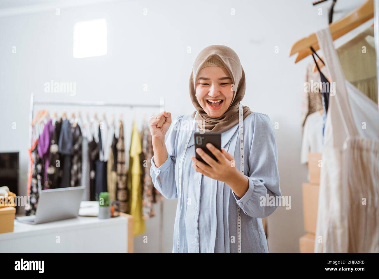 excited asian muslim woman small business owner look at phone Stock Photo