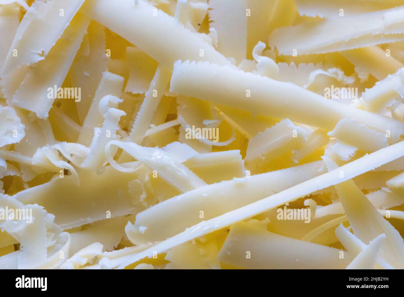 Macro shot of grated cheddar cheese on top of an uncooked lasagne