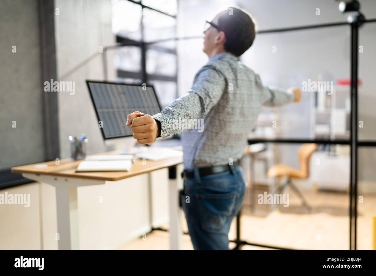 Man Doing Stretch Exercise At Work In Office Stock Photo