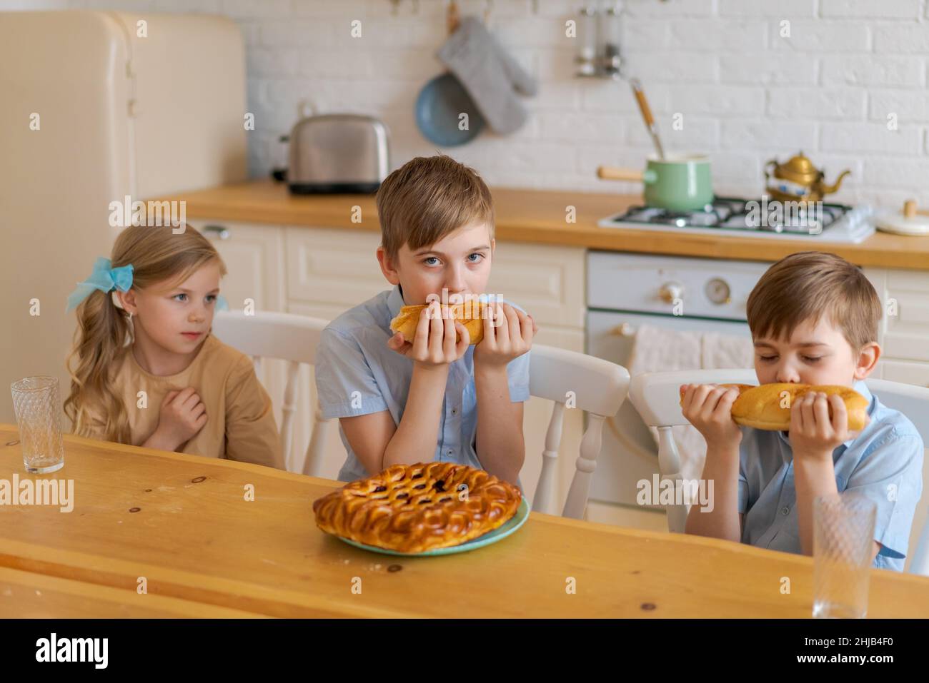 https://c8.alamy.com/comp/2HJB4F0/cheerful-children-are-sitting-at-table-in-kitchen-playing-with-loaf-bread-while-waiting-for-food-two-brothers-and-sister-have-fun-at-dinner-at-home-family-spend-time-together-at-home-on-weekend-2HJB4F0.jpg