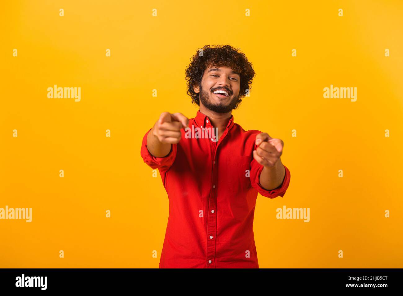 Portrait of cheerful bearded man pointing to camera, smiling, making happy choice, we need you concept. Indoor studio shot isolated on orange background Stock Photo