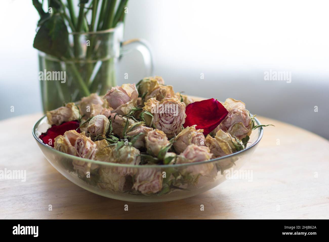Dry rose buds in glass bowl and stems in glass with water. Concept for
