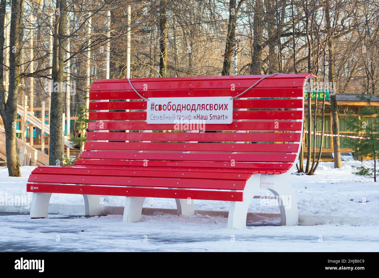 Cheboksary Russia - 12 December 2019: Big red bench in winter park in Lakreevskiy forest. Translation: Free for ours, Family tarif Our Smart, MTC Stock Photo