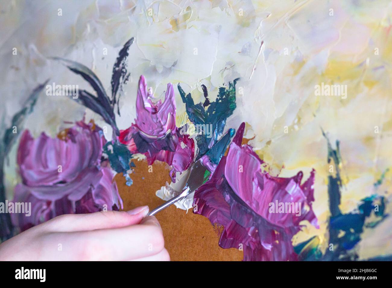 Woman hands painting with palette knife flowers by oil paints on