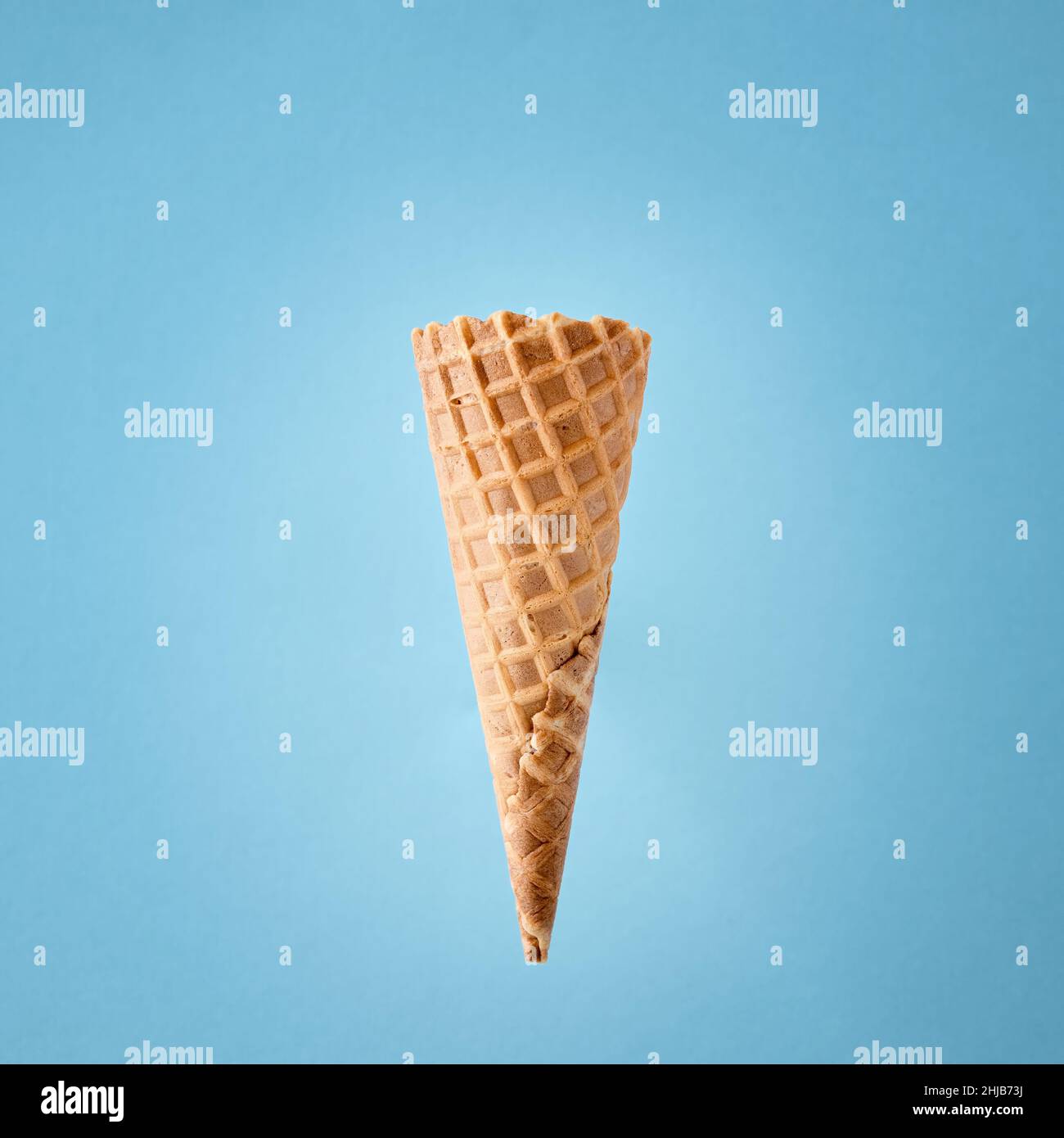 Empty wafer ice cream cone on blue background. Stock Photo
