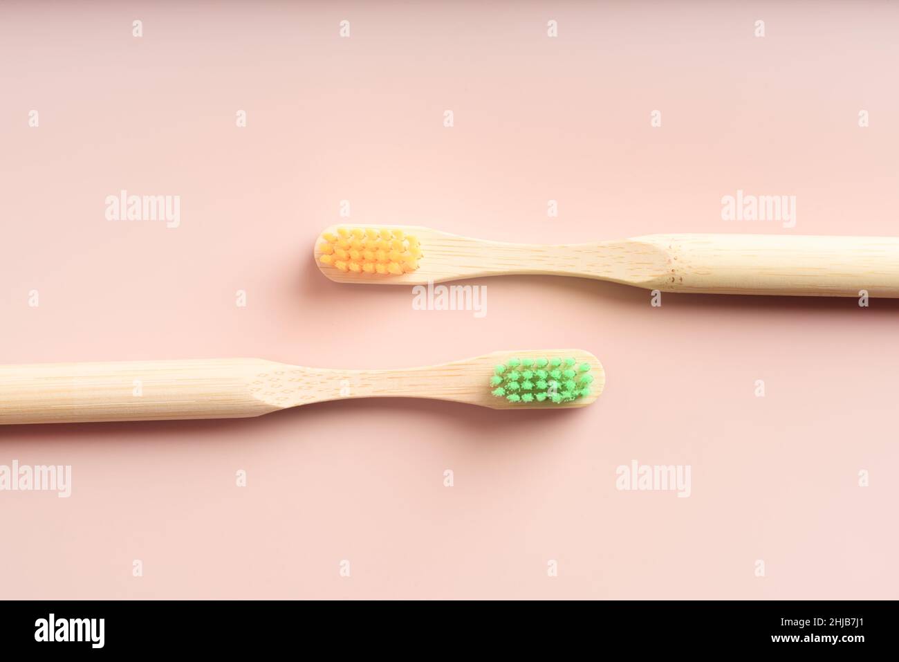 Two yellow and green eco friendly natural bamboo toothbrushes on pink ...