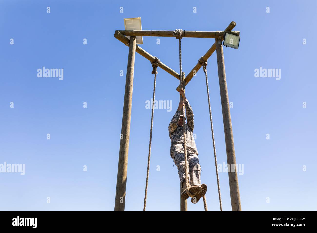 Caucasian male soldier rope climbing during obstacle course at boot camp Stock Photo
