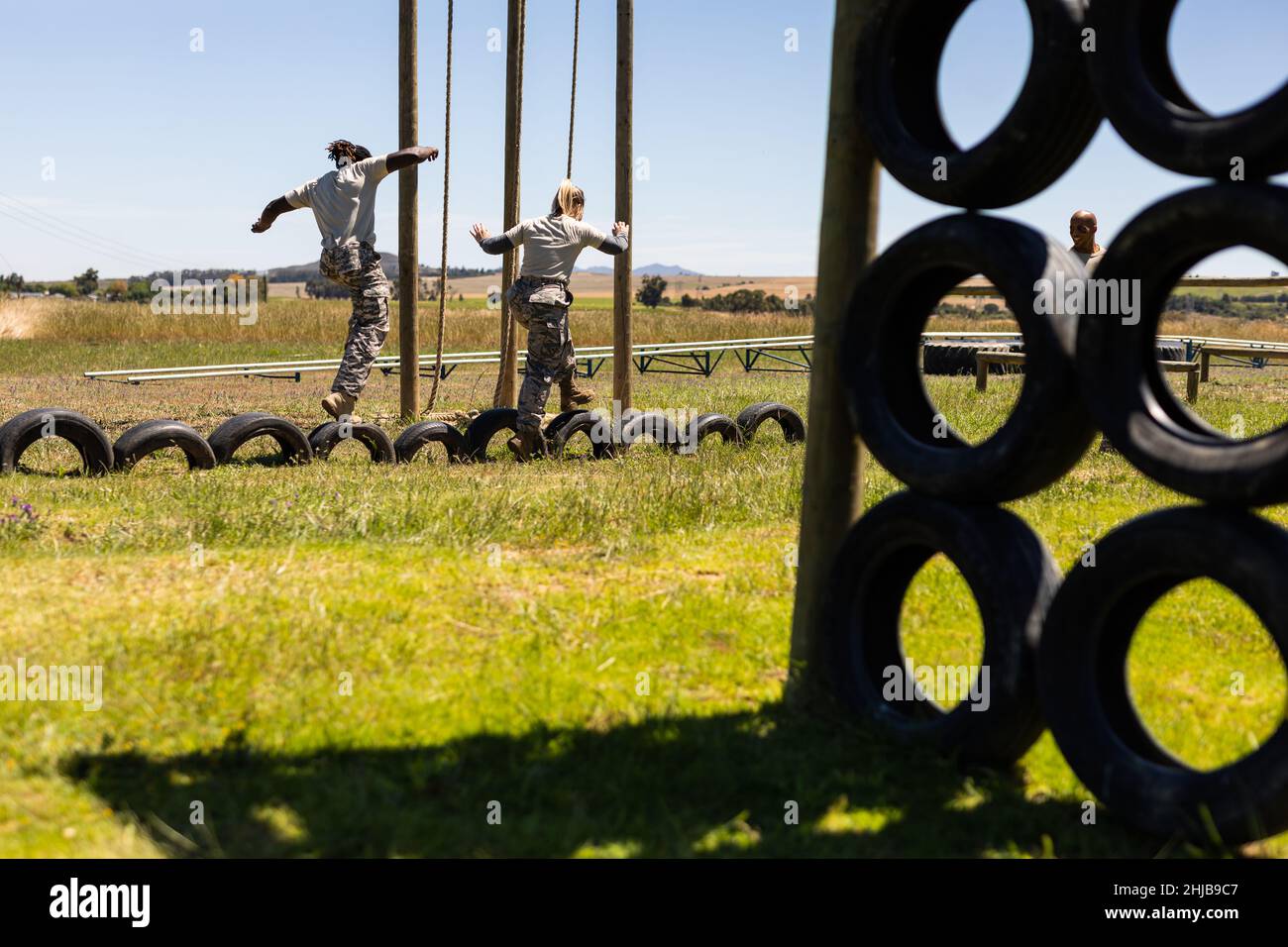 Diverse male and female soldiers walking on tires during obstacle course at boot camp Stock Photo