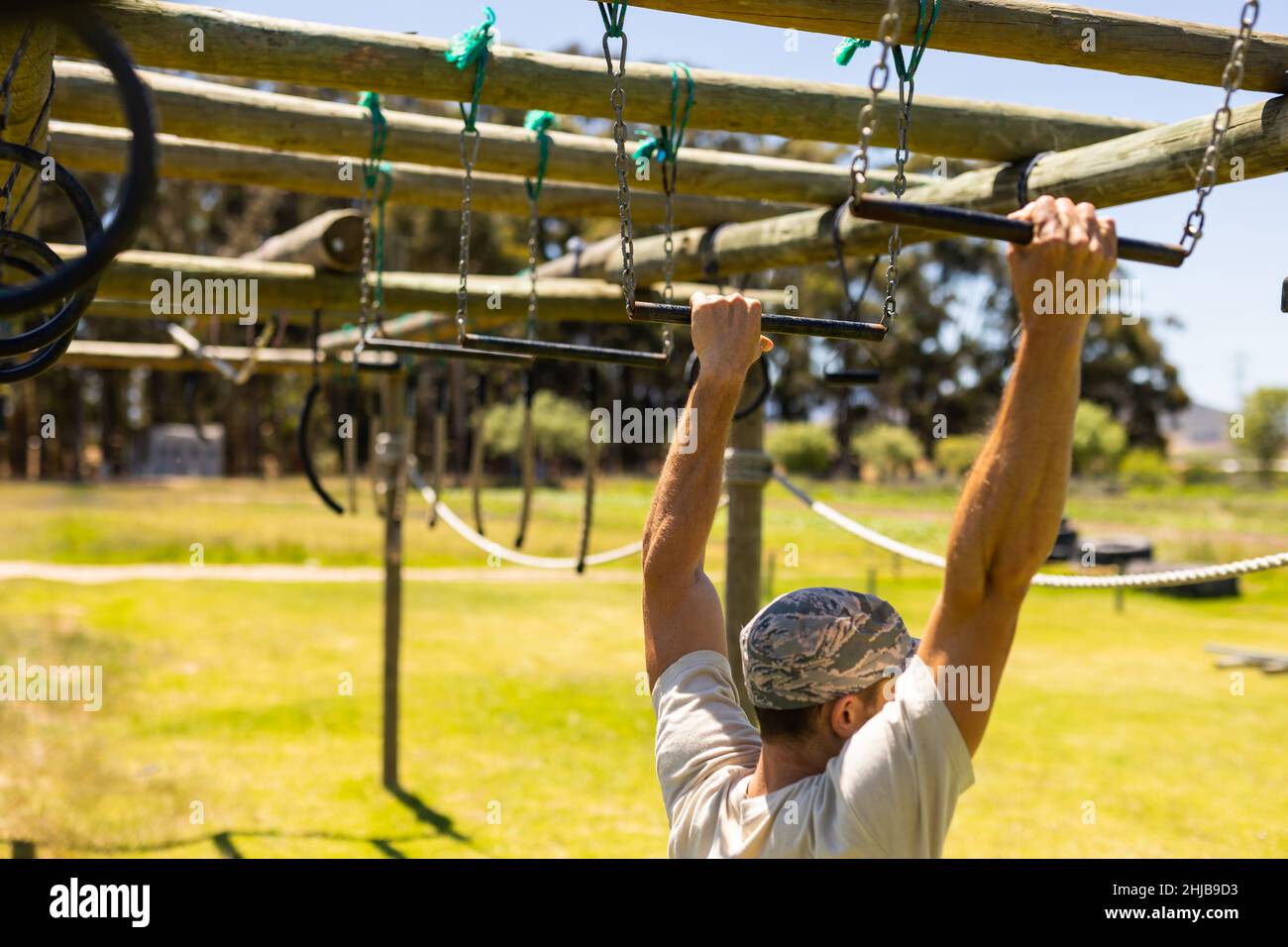 Caucasian male soldier climbing monkey bars during obstacle course at boot camp Stock Photo