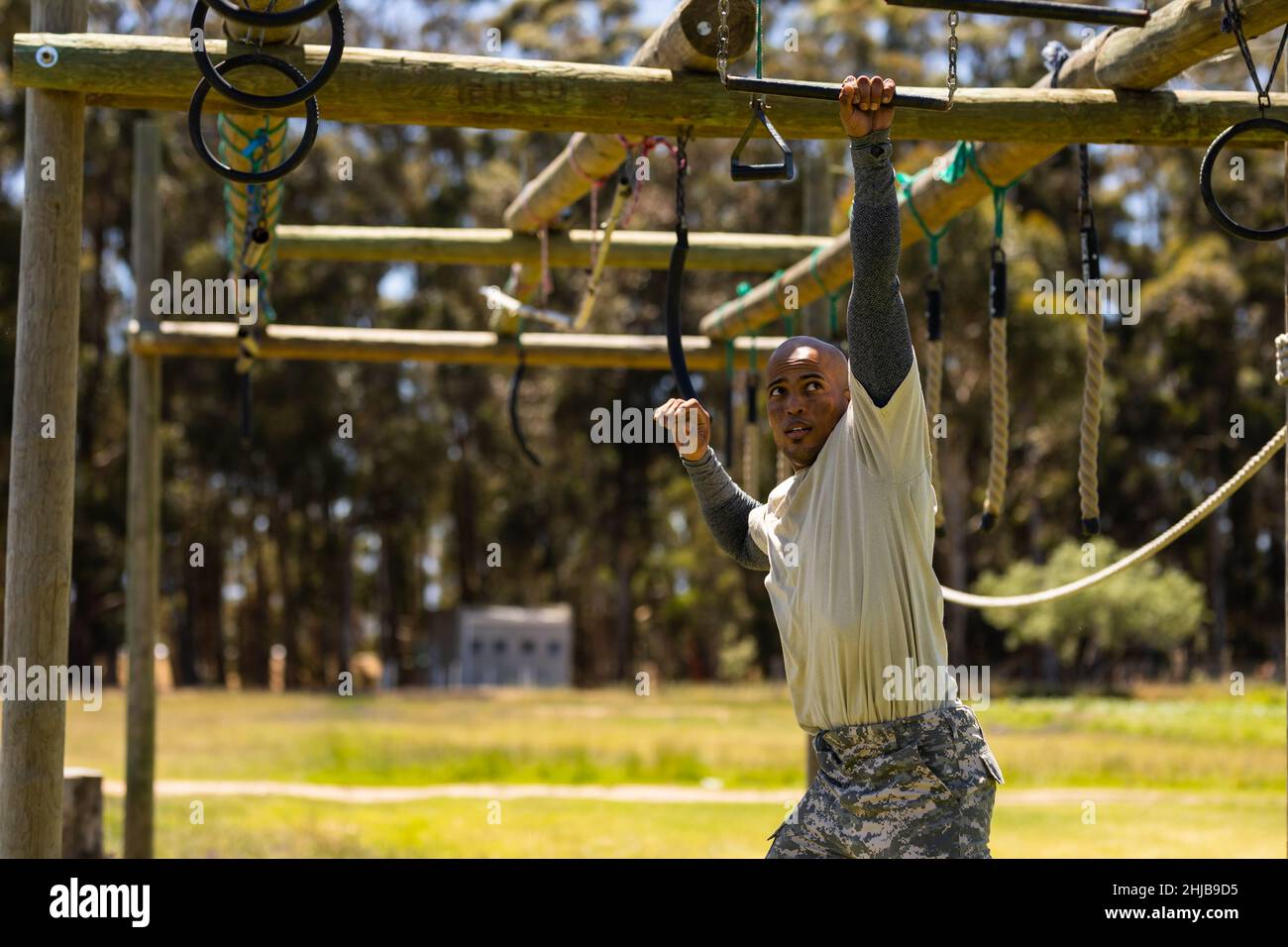 African american male soldier climbing monkey bars during obstacle course at boot camp Stock Photo