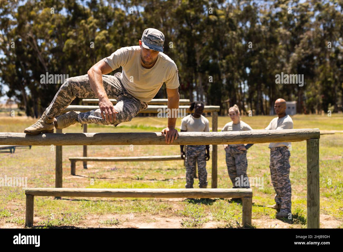 Caucasian male soldier jumping over wooden hurdles during obstacle course at boot camp Stock Photo